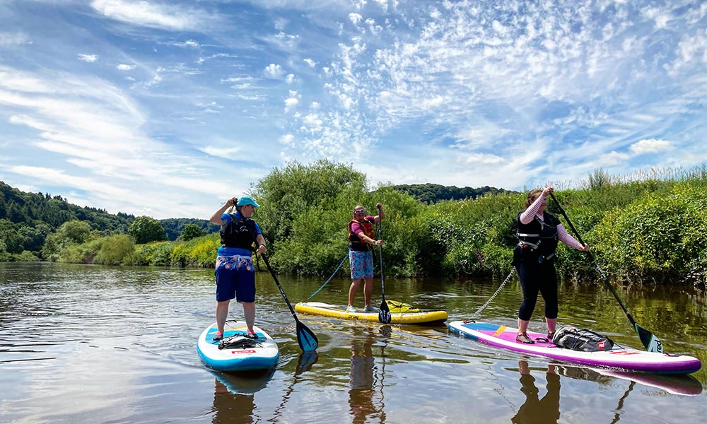 Paddle Boarding Tips - 3 people enjoying SUP on a river in the summer