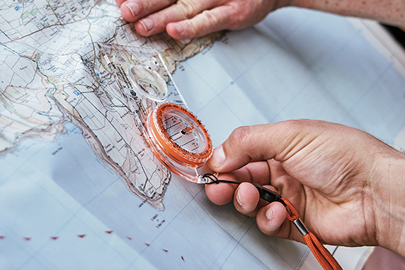 Close up of a person using a compass on a map