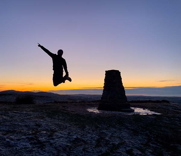 Adrian Conchie jumping off a trig pillar
