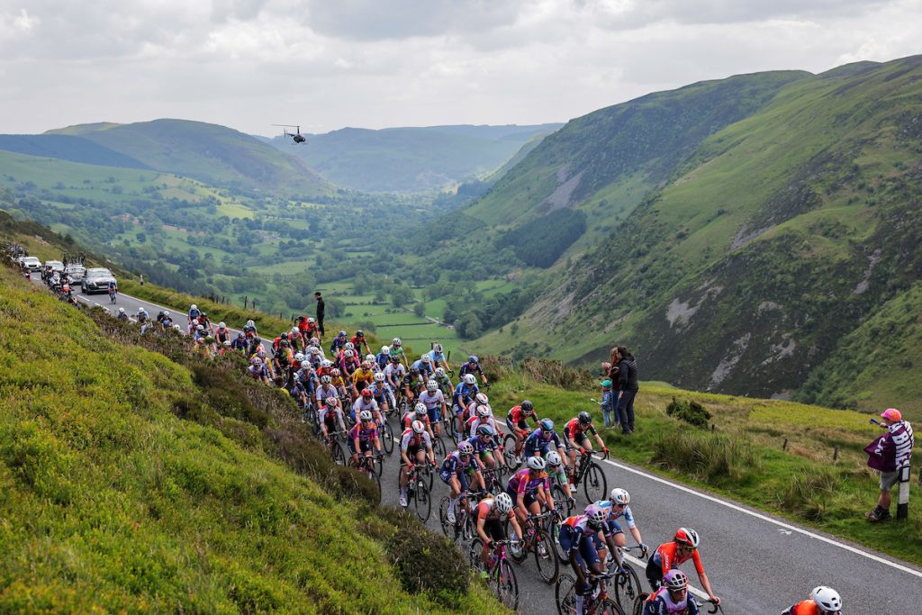 Large group of cyclists being followed by a helicopter up a mountain pass