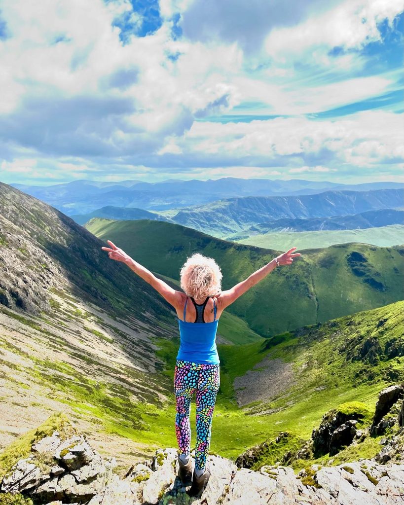 claires outdoor adventures - claire in the mountains with arms aloft