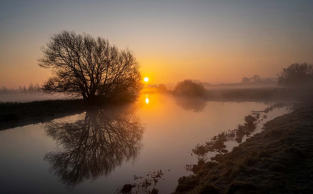 Misty sunrise with reflections on the River Nene in Fotheringhay