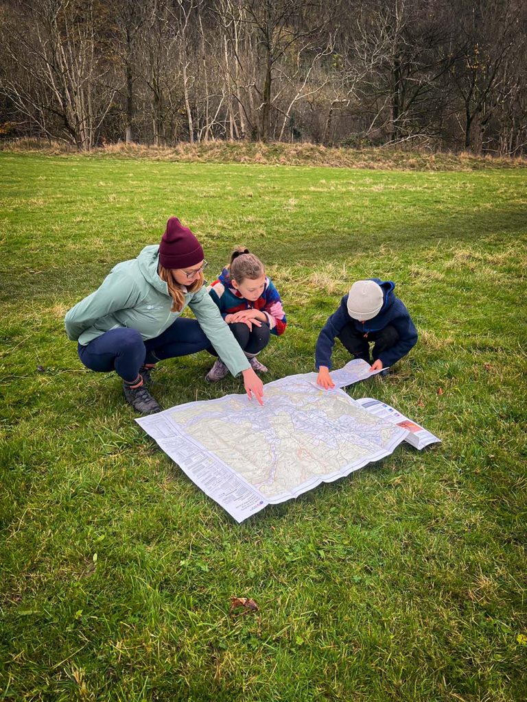 Mum and kids route planning with personalised os map on the grass
