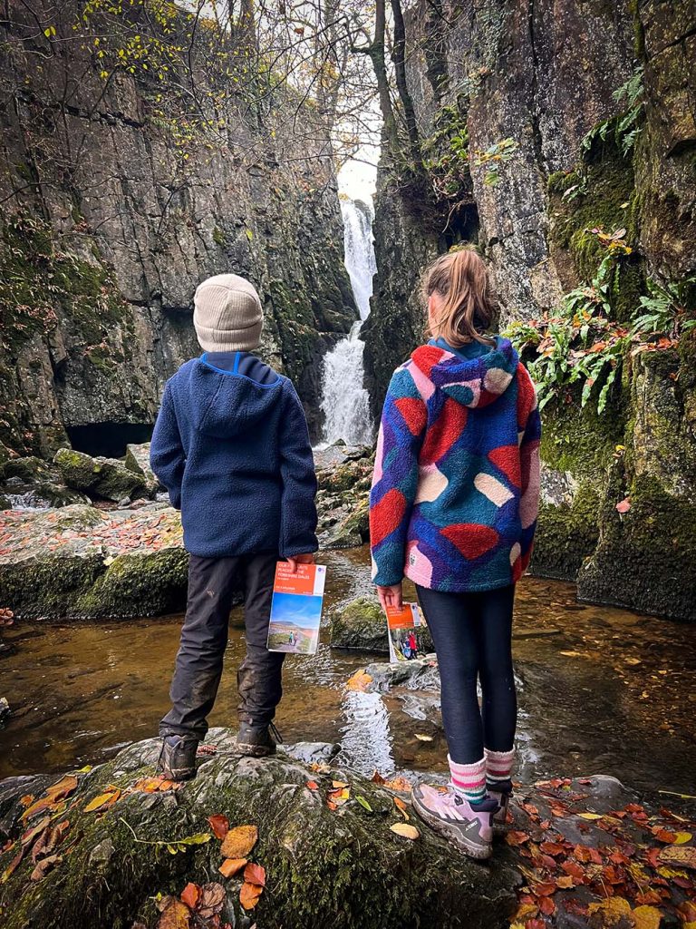 kids with a personalised map in front of a waterfall the Yorkshire Dales
