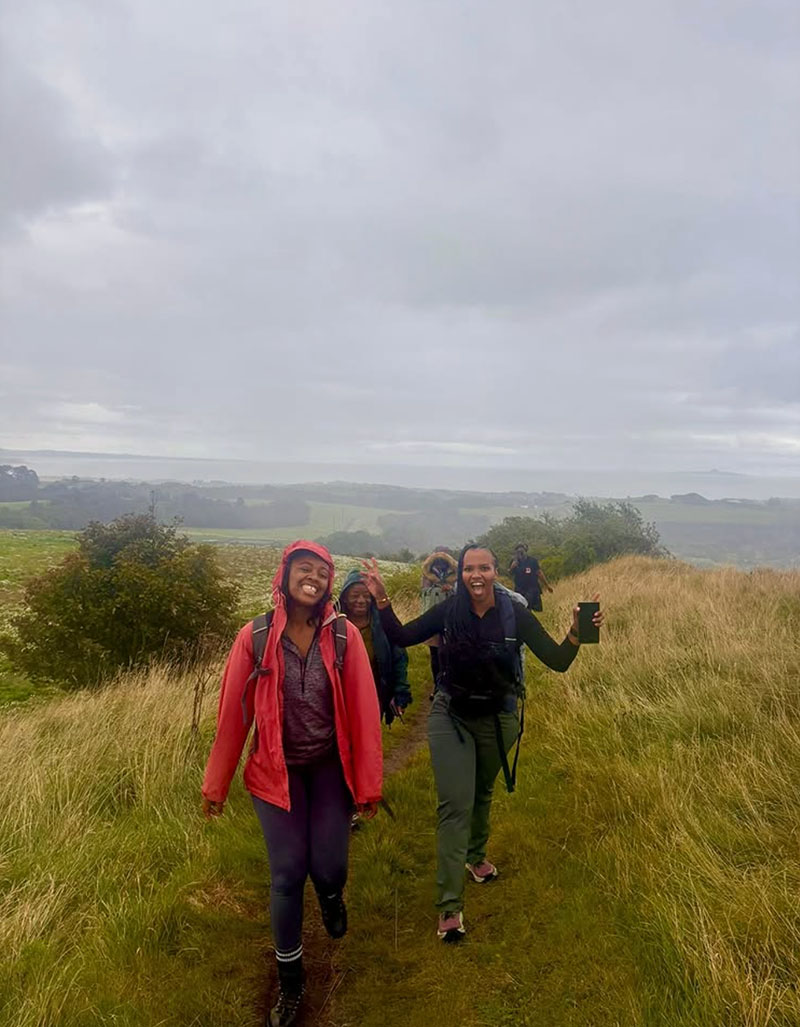 Two black women walking up a steep path on a hill