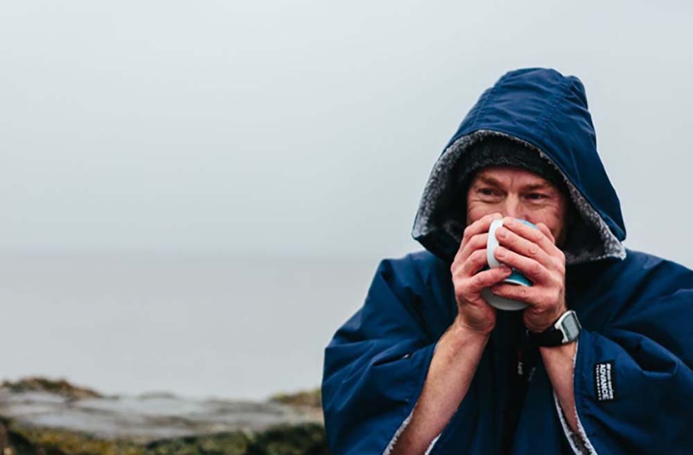 a man in a dry robe with a hot cup of coffee in his hands