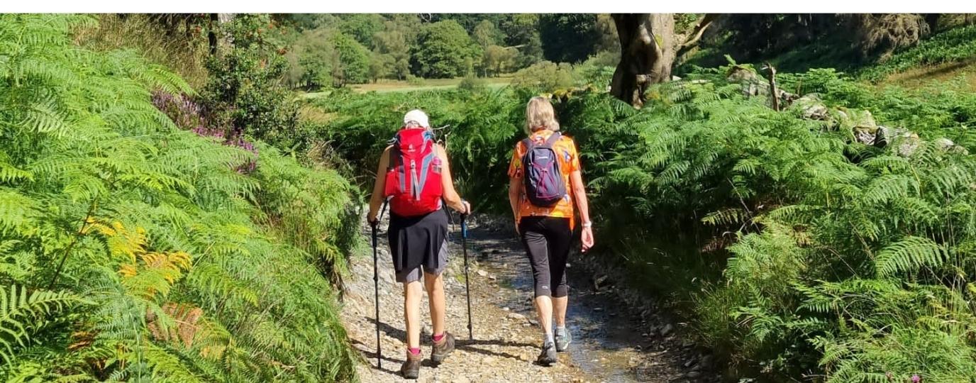 a pair of women walking up a track with back packs on