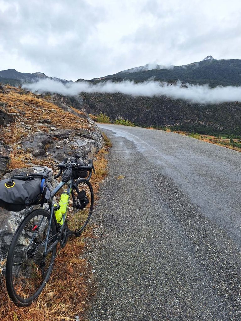 Bikepacking in the Alps - clouds and mountains with a bike in the foreground