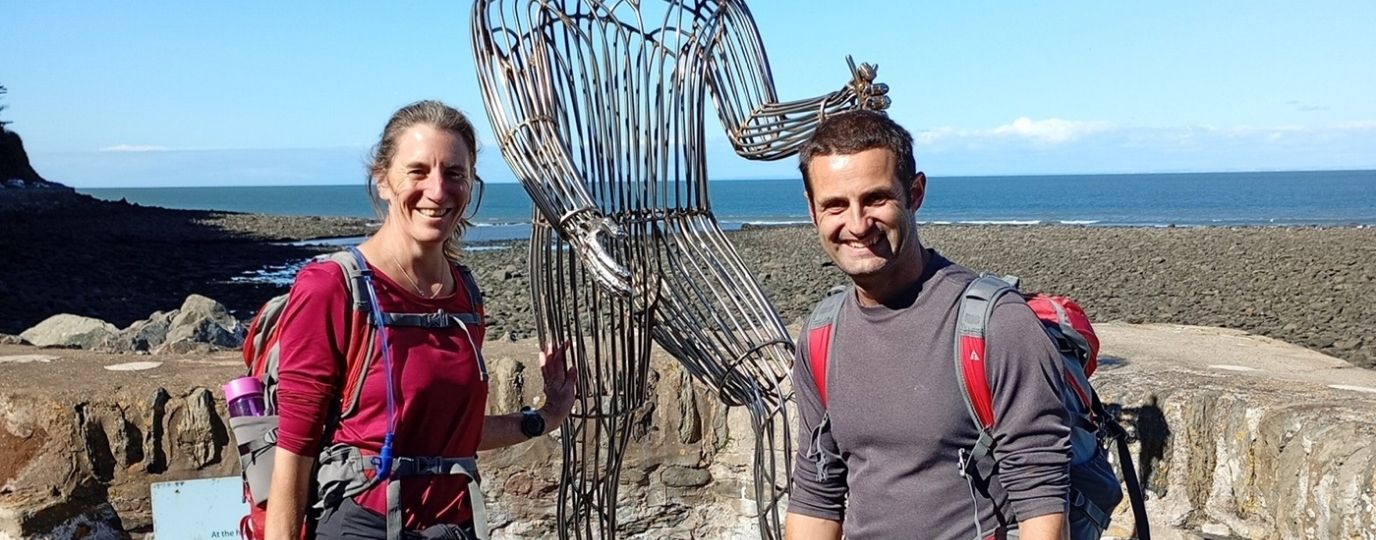 a couple on a walking holiday in front of a statue