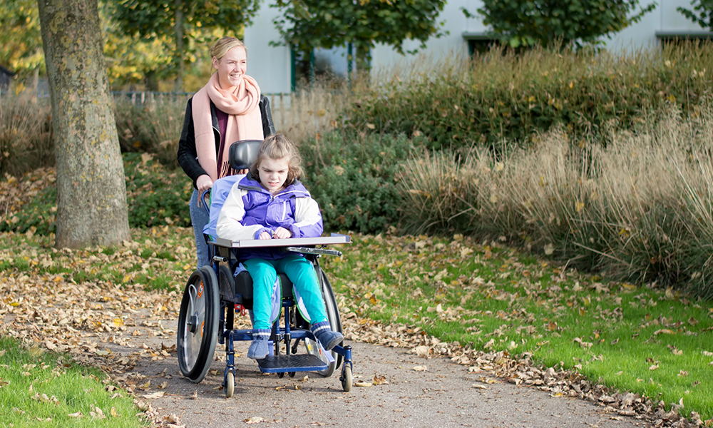 woman pushing a wheelchair on a walk