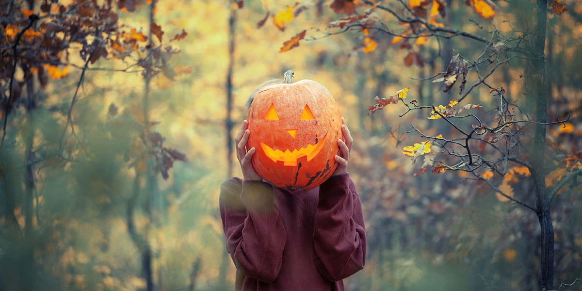 Boy holding pumpkin in front of face